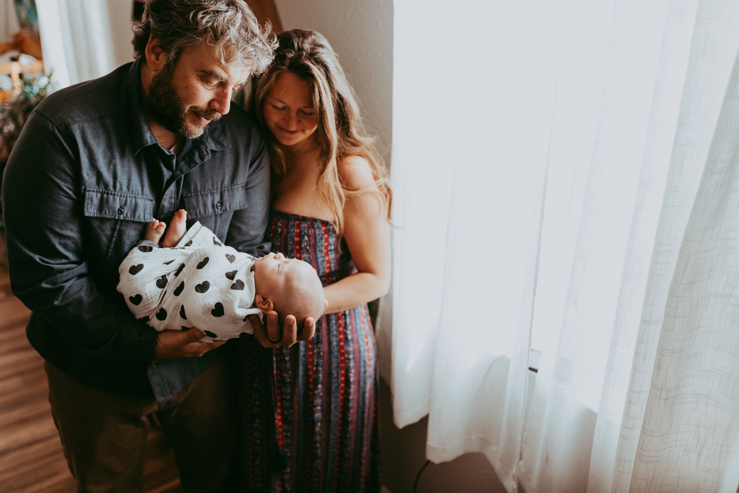 New Parents look down at newborn baby, newborn lifestyle photography