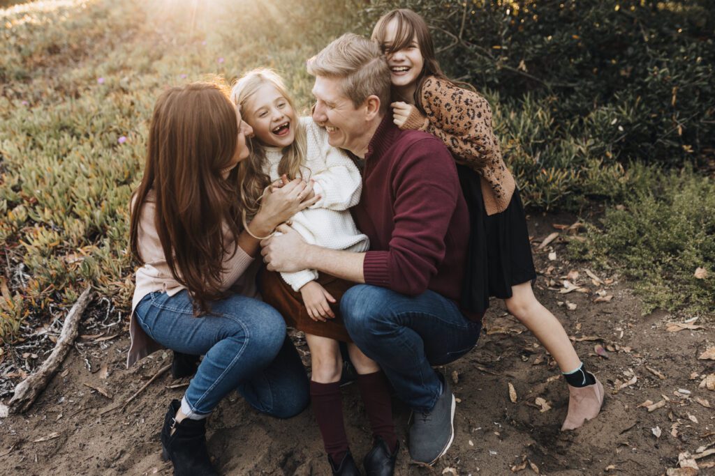 A family doubles over in laughter as they snuggle up.