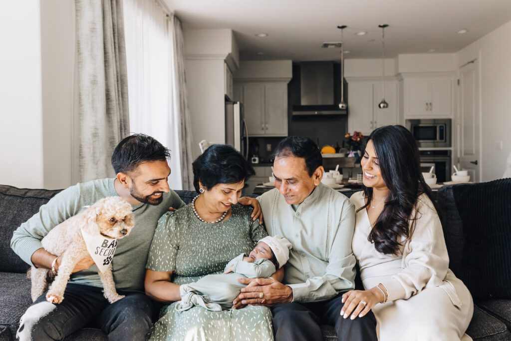 Family smiles at baby including grandparents and dog_Lifestyle Newborn Photographer