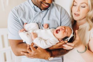 Baby held by her parents yawns during lifestyle newborn session