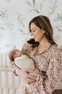 Mom holds newborn baby at home in nursery