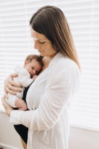 Mom holds baby on her chest during lifestyle newborn session