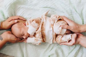 Sleeping baby is held by her parents hands
