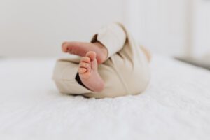 Baby is scrunched up on the bed with his feet in the air. Photo is of his feet