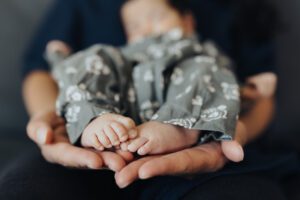 Baby feet are supported by her mothers hands