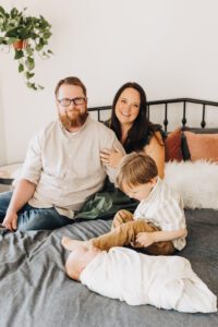Whole family on the bed with baby sister swaddled during lifestyle newborn session