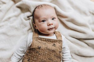 Three month old baby smiles up at the camera in-home session