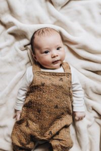 Three month old baby smiles at the camera during in-home session