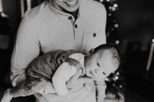 Black and white of dad holding baby like a koala